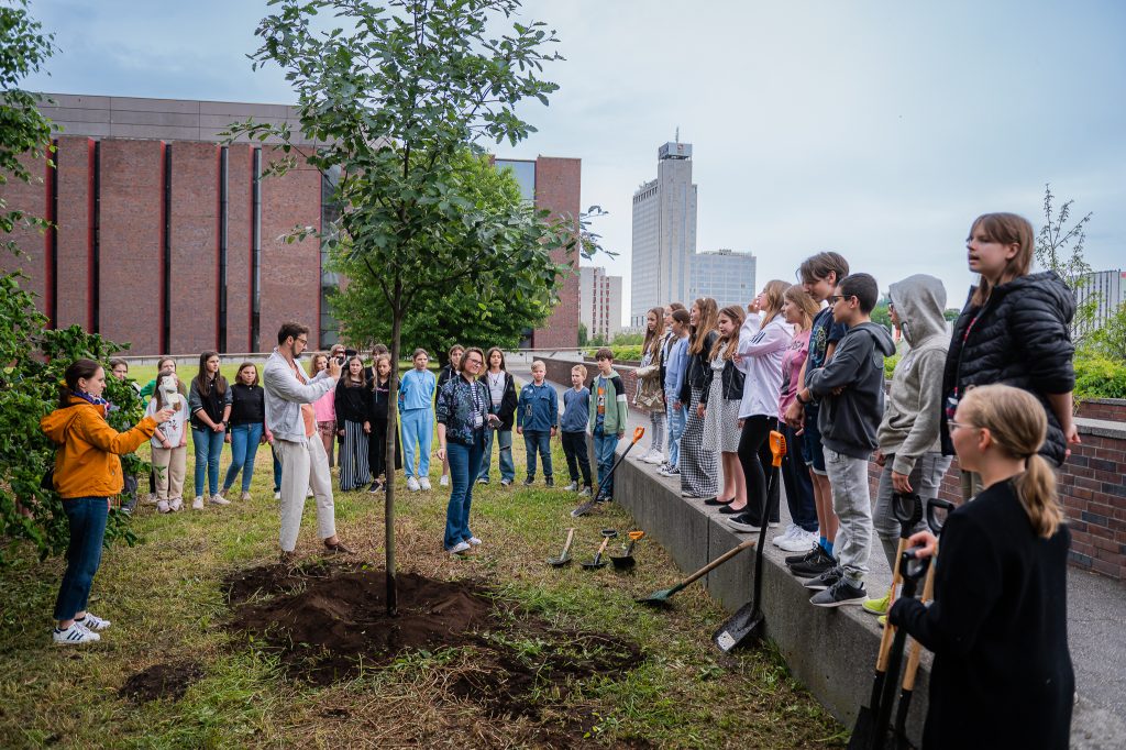 Students and teachers planting sapling outside.