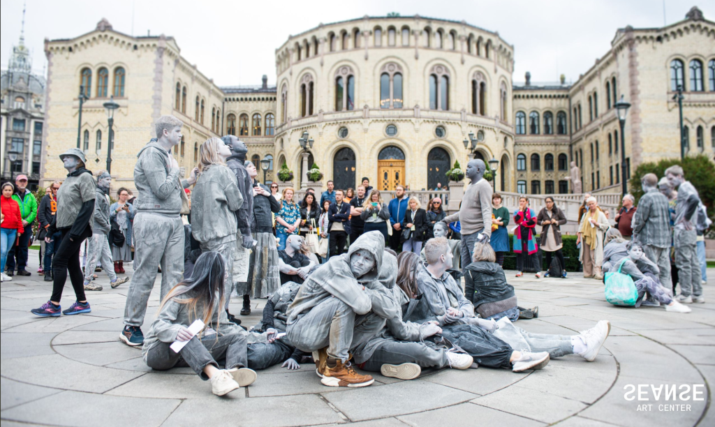 Performers in town square with performers covered in ash